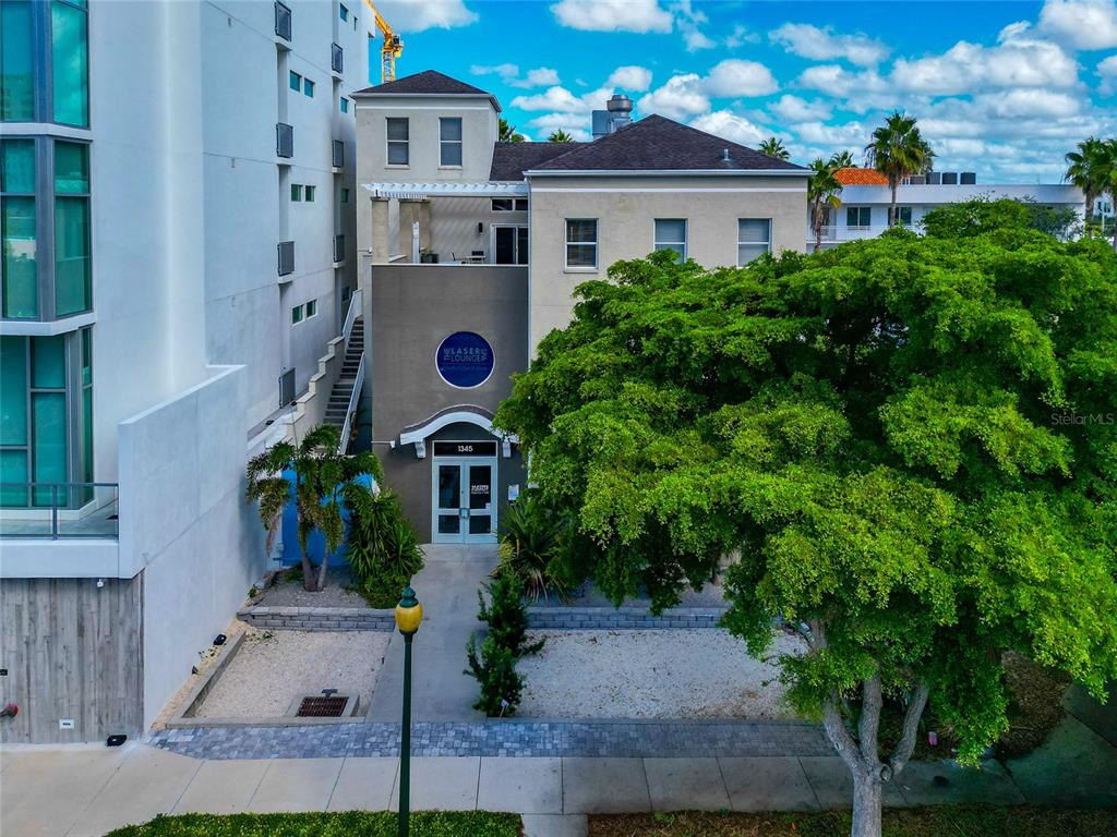 An exterior view of a two-story building with a front entrance and a large tree — 1345 2ND STREET, SARASOTA, FL