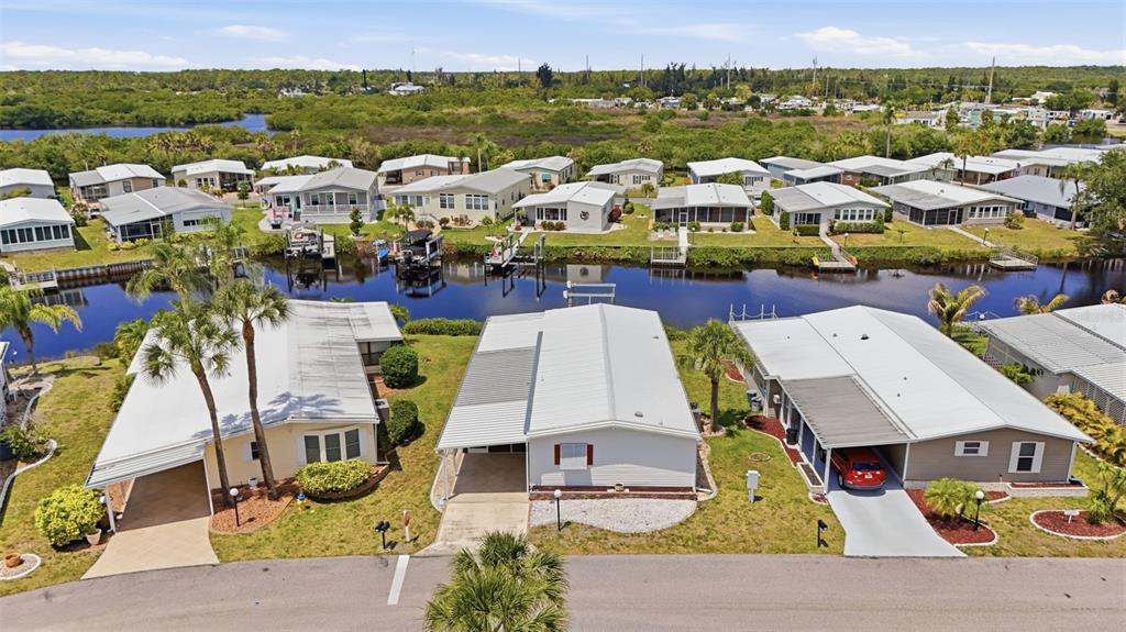 An aerial view shows several mobile homes along a canal with palm trees and landscaping — 118 MARTINIQUE ROAD, NORTH PORT, FL