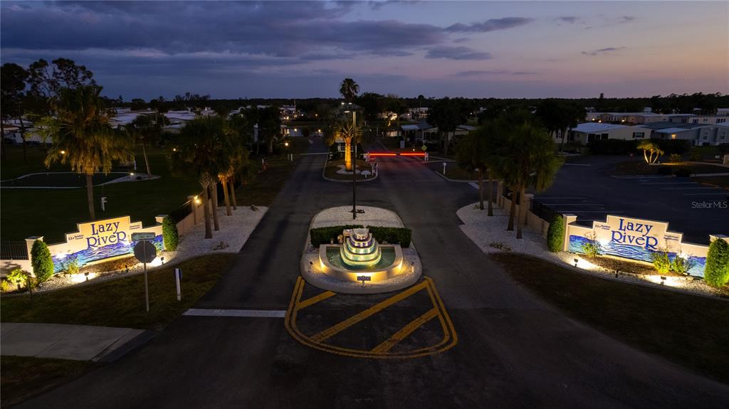 An aerial view shows the gated entrance to Lazy River with a central fountain — 118 MARTINIQUE ROAD, NORTH PORT, FL