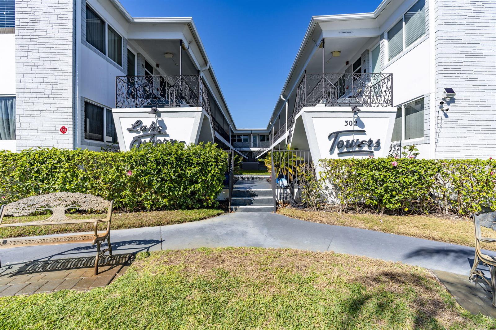 The exterior of a two-story apartment building features white brick walls and a central walkway — 302 Lake Osborne Drive # 5, FL 33461, FL