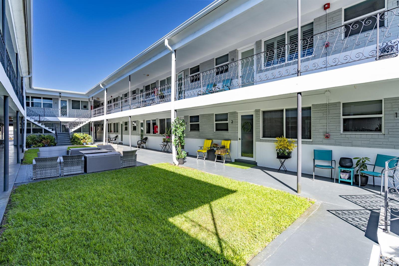 An exterior view of a two-story apartment complex with a central courtyard and lawn — 302 Lake Osborne Drive # 5, FL 33461, FL