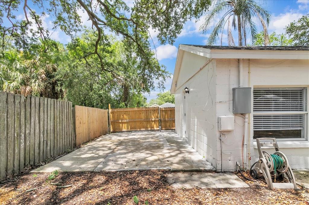 A concrete patio area sits beside a white block building with a wooden fence — 6008 N TAMPA STREET UNIT 2, TAMPA, FL