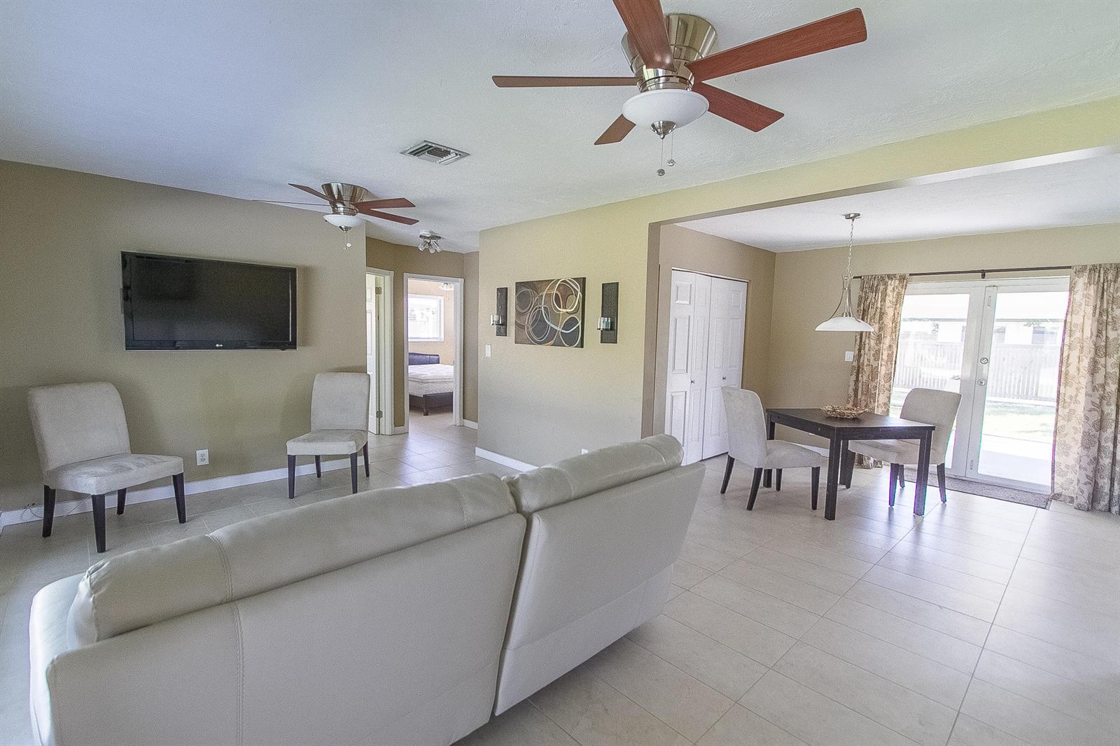 A living room and dining area feature tile floors, ceiling fans, and neutral wall colors — 116 NW 8th Street, Boca Raton FL 33432, BOCA RATON, FL