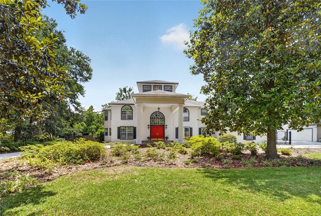 A two-story white house with a red front door and a large covered entryway — 7815 NW 20TH LANE, GAINESVILLE, FL