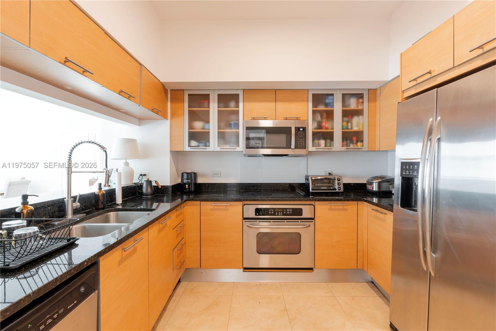 A kitchen features light wood cabinets, stainless steel appliances, and black granite countertops — 31 SE 5th St # 4121, Miami FL 33131, MIAMI, FL