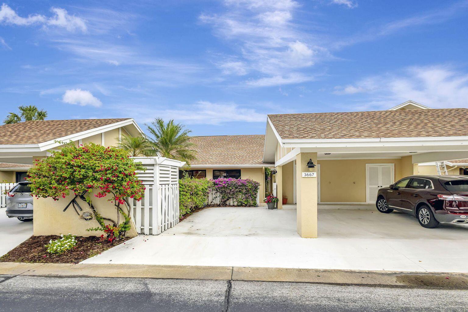 A single-story residential building with a concrete driveway, carport, and a white privacy fence — 3667 Cape Pointe Circle, Jupiter FL 33477, JUPITER, FL
