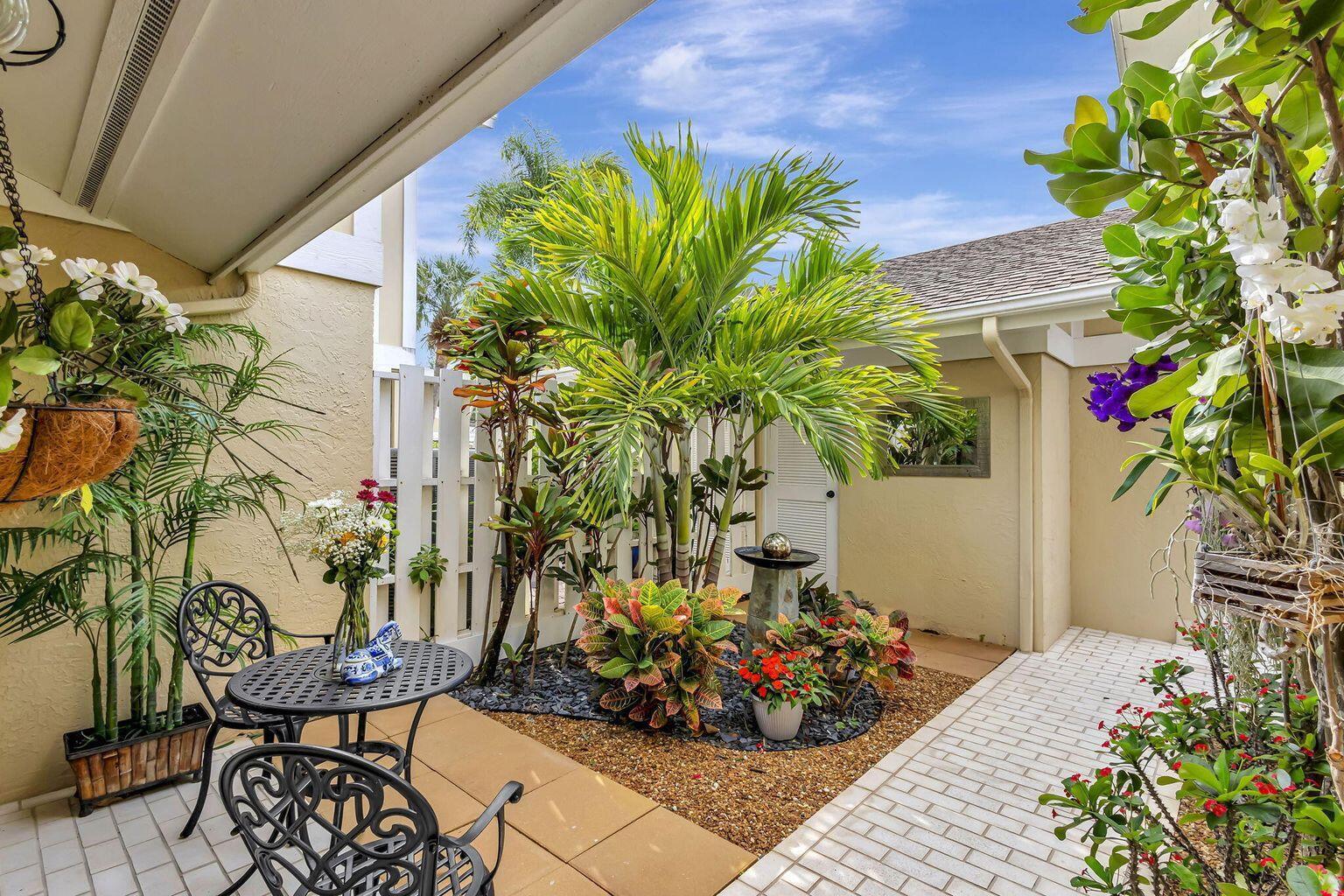 A small patio features a bistro set, lush tropical plants, and a decorative water fountain — 3667 Cape Pointe Circle, Jupiter FL 33477, JUPITER, FL
