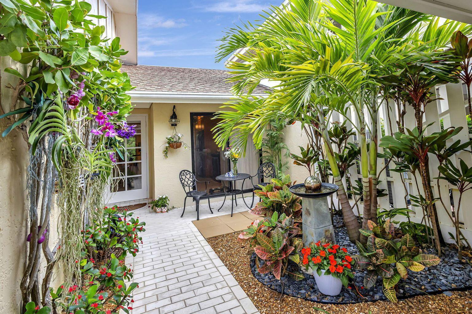 A paved walkway leads to a patio with a bistro set and tropical landscaping — 3667 Cape Pointe Circle, Jupiter FL 33477, JUPITER, FL