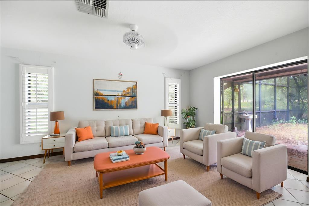 A living room features a beige sofa, two armchairs, an orange coffee table, and tile flooring — 4444 RAINES ROAD, BROOKSVILLE, FL