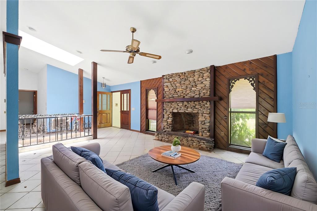 A living room features a stone fireplace, wood paneling, tile floors, and blue walls — 4444 RAINES ROAD, BROOKSVILLE, FL