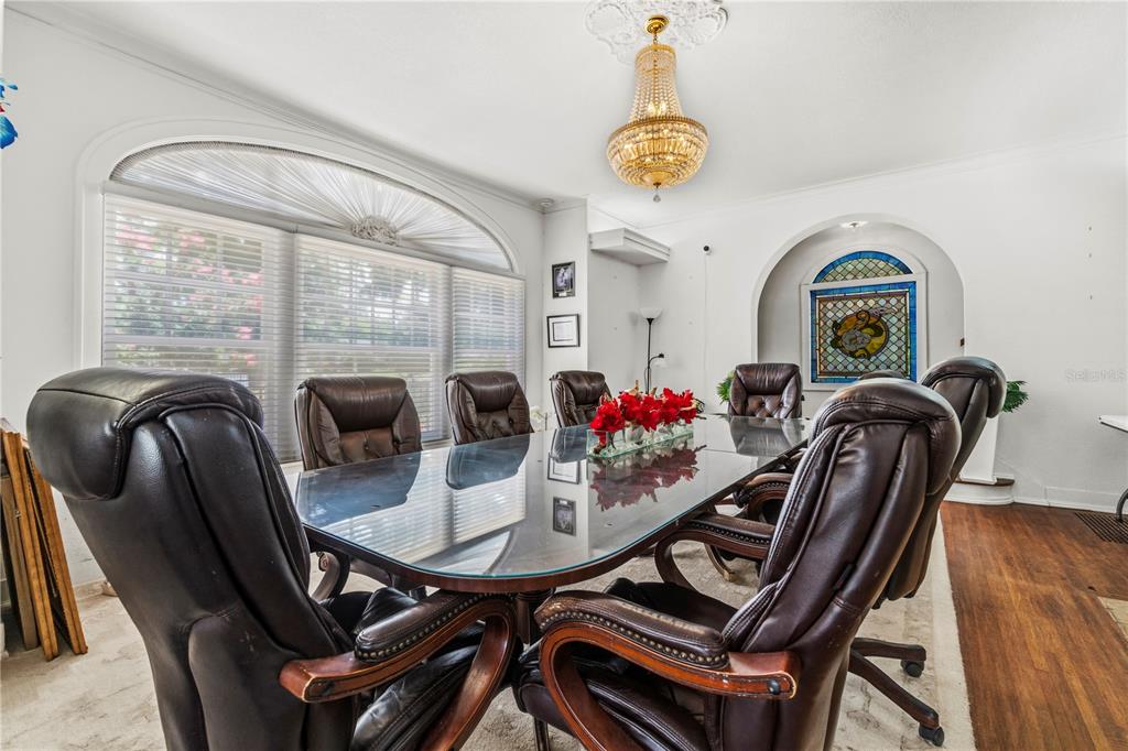 A dining room features a glass-topped table, leather chairs, a crystal chandelier, and stained glass — 3610 E FORT KING STREET, OCALA, FL
