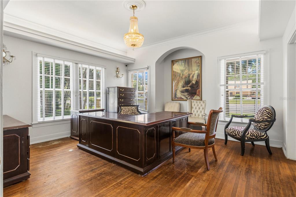 A home office features a large wooden desk, hardwood floors, and a crystal chandelier — 3610 E FORT KING STREET, OCALA, FL