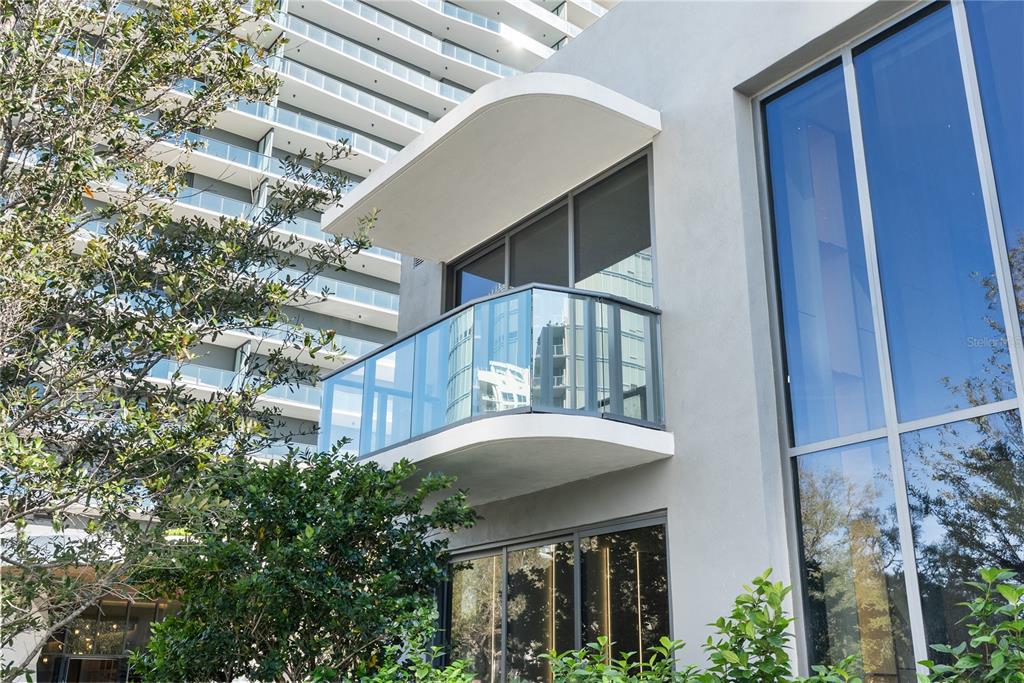 A modern building exterior features a curved balcony with glass railings and large windows — 3020 W SANTIAGO STREET UNIT 1, TAMPA, FL