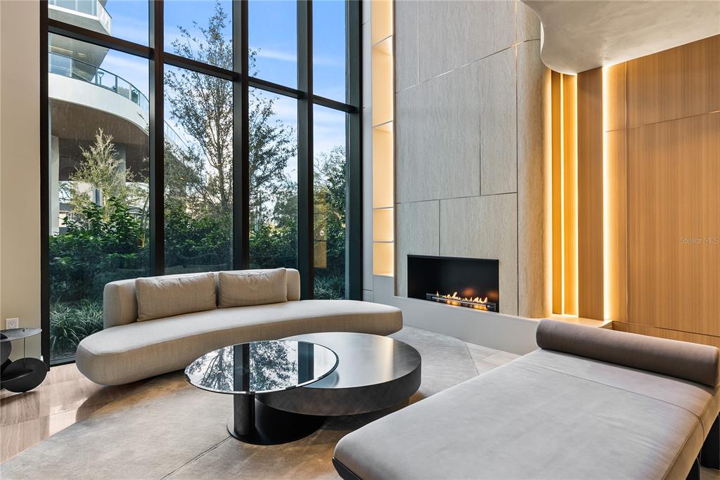 A modern living room features floor-to-ceiling windows, a linear fireplace, and contemporary furniture — 3020 W SANTIAGO STREET UNIT 1, TAMPA, FL