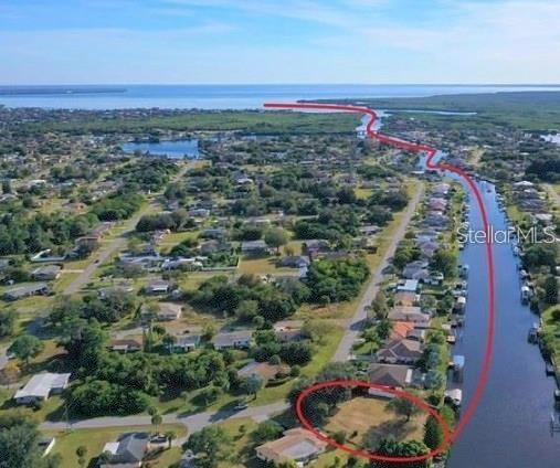 An aerial view shows a vacant residential lot next to a canal leading to the bay — 550 E TARPON BOULEVARD NW, PORT CHARLOTTE, FL