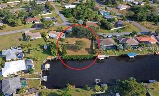 An aerial view shows a vacant waterfront lot circled in red along a canal — 550 E TARPON BOULEVARD NW, PORT CHARLOTTE, FL