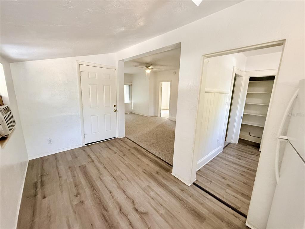 A room with wood-look flooring leads to a carpeted living area and a pantry — 1135 HIGHLAND STREET N UNIT 7, ST PETERSBURG, FL