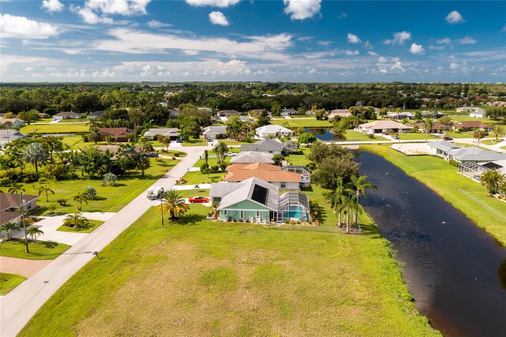 An aerial view shows a residential neighborhood with houses, a canal, and green lawns — 19 BUNKER TERRACE, ROTONDA WEST, FL