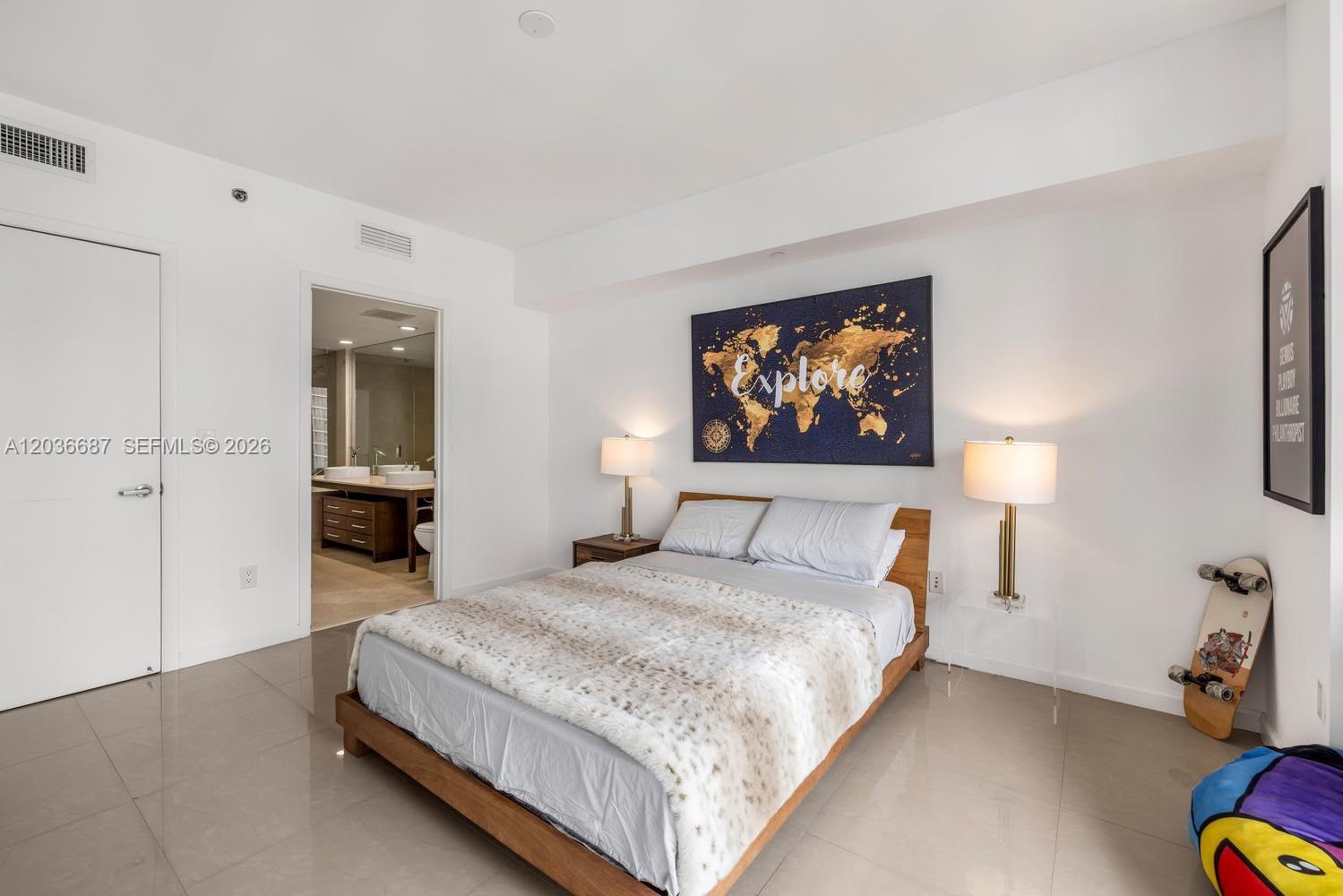 A bedroom features a wooden bed frame, a world map wall art, and an attached bathroom — 475 Brickell Ave # 3214, Miami FL 33131, MIAMI, FL