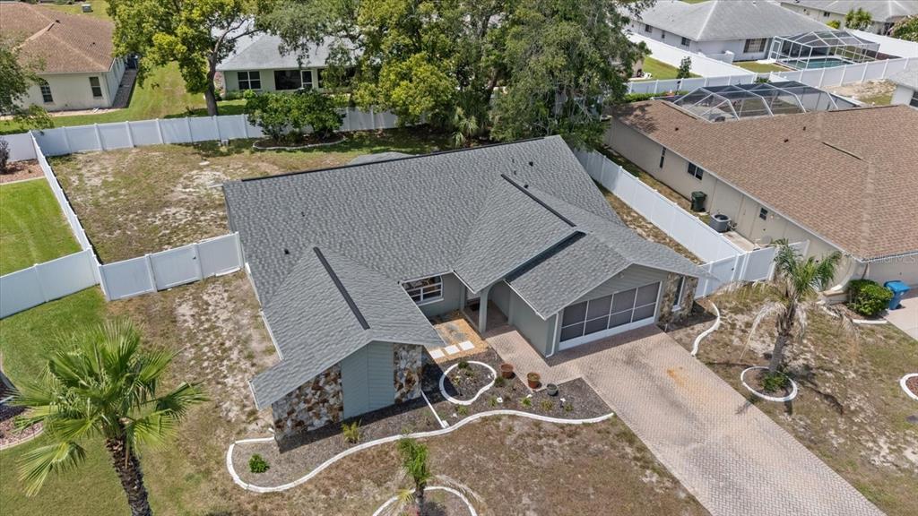 An aerial view shows a single-story house with a gray roof and stone accents — 8166 WINDING OAK LANE, SPRING HILL, FL