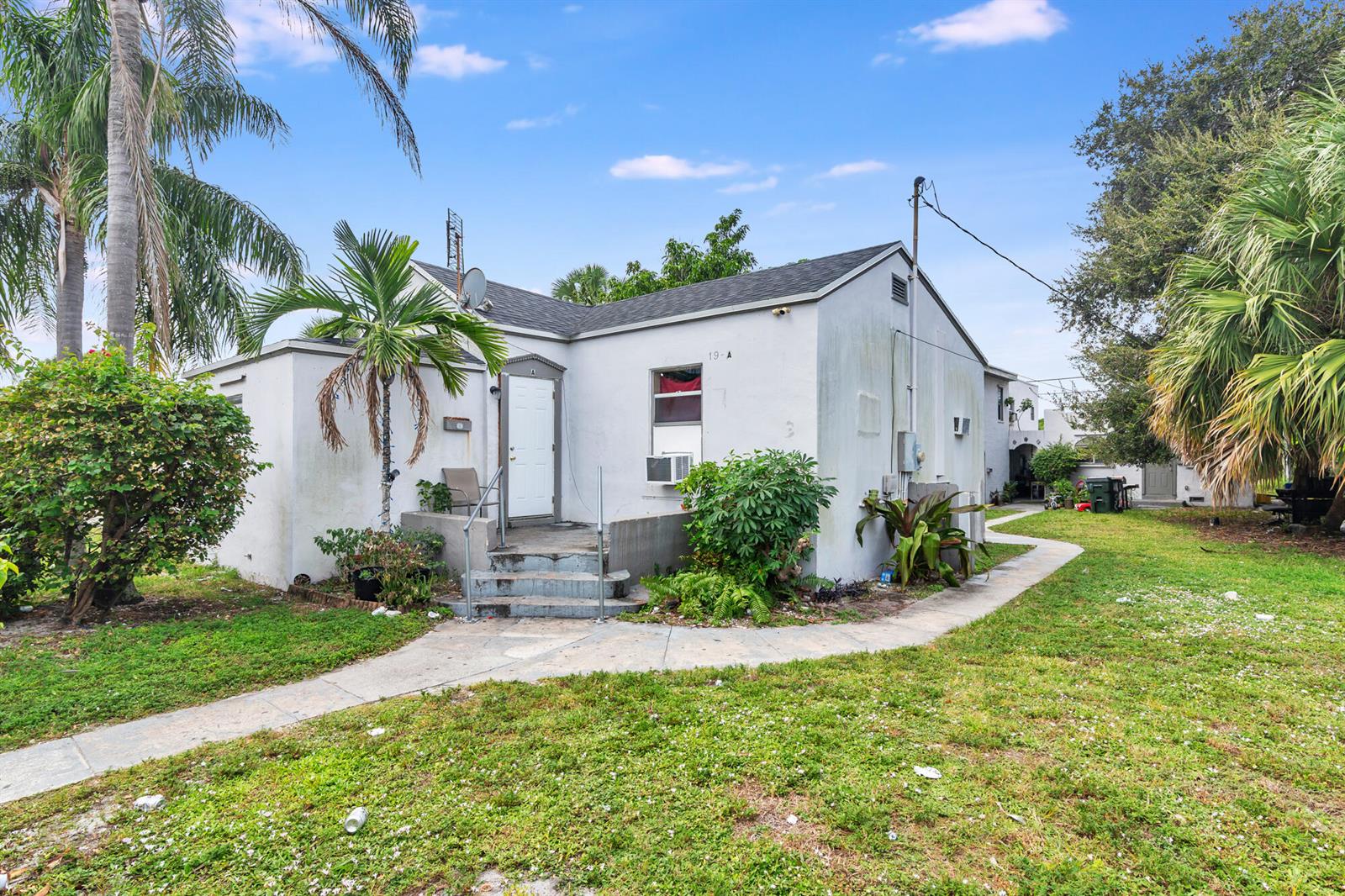 A single-story white house with a front porch, stairs, and a palm tree in the yard — 19 S E Street, FL 33460, FL