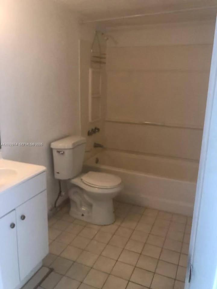 A bathroom features a white vanity, a toilet, and a shower-tub combination with tiled floors — 6155 NW 186th St # 209, Hialeah FL 33015, HIALEAH, FL