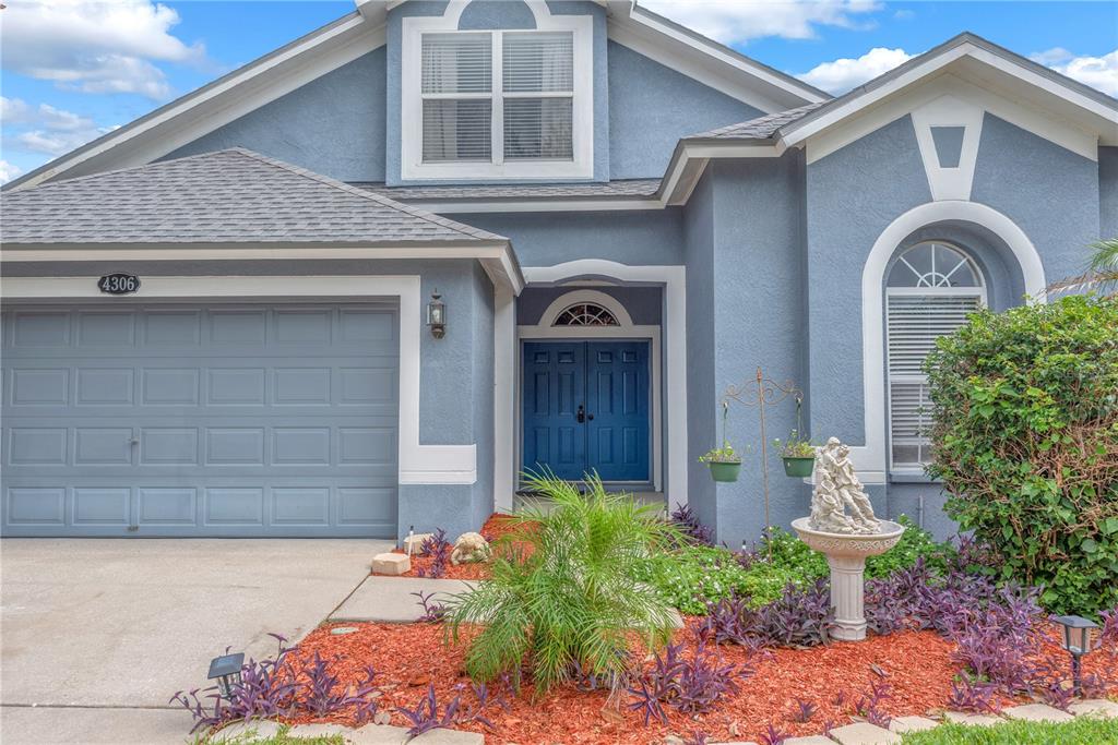 A blue house with a two-car garage, double front doors, and a landscaped front yard — 4306 ORANGE RIDGE COURT, VALRICO, FL