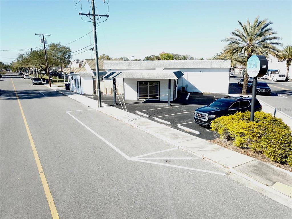 An exterior view of a white commercial building with a parking lot and signage — 212 MAIN STREET, AUBURNDALE, FL