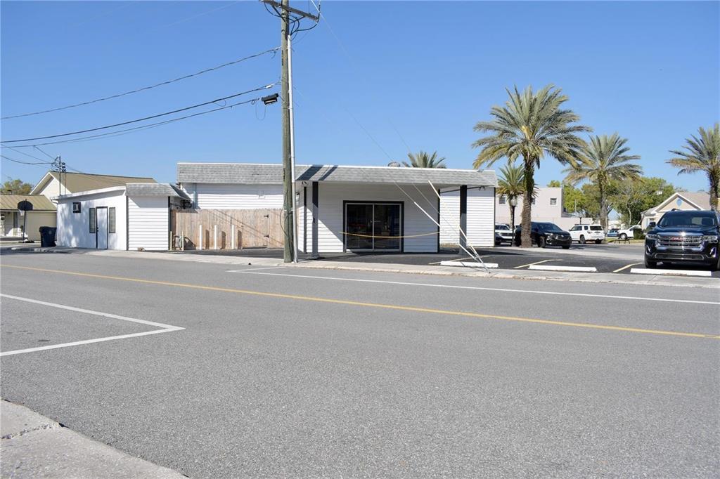 A single-story commercial building with white siding and a parking lot sits along a road — 212 MAIN STREET, AUBURNDALE, FL
