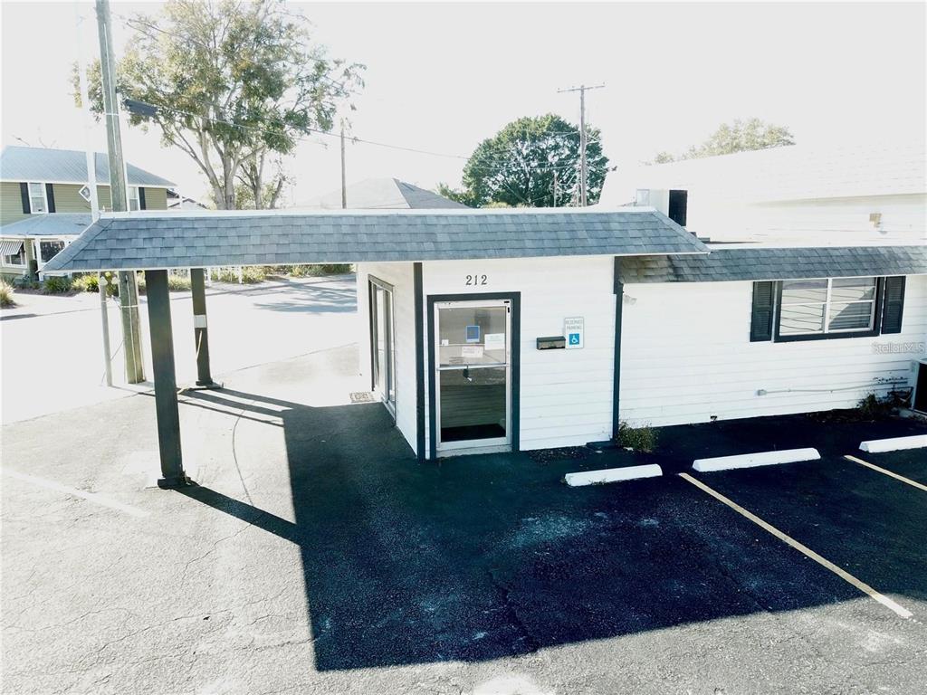 An exterior view of a white commercial building with a covered entrance and parking spaces — 212 MAIN STREET, AUBURNDALE, FL