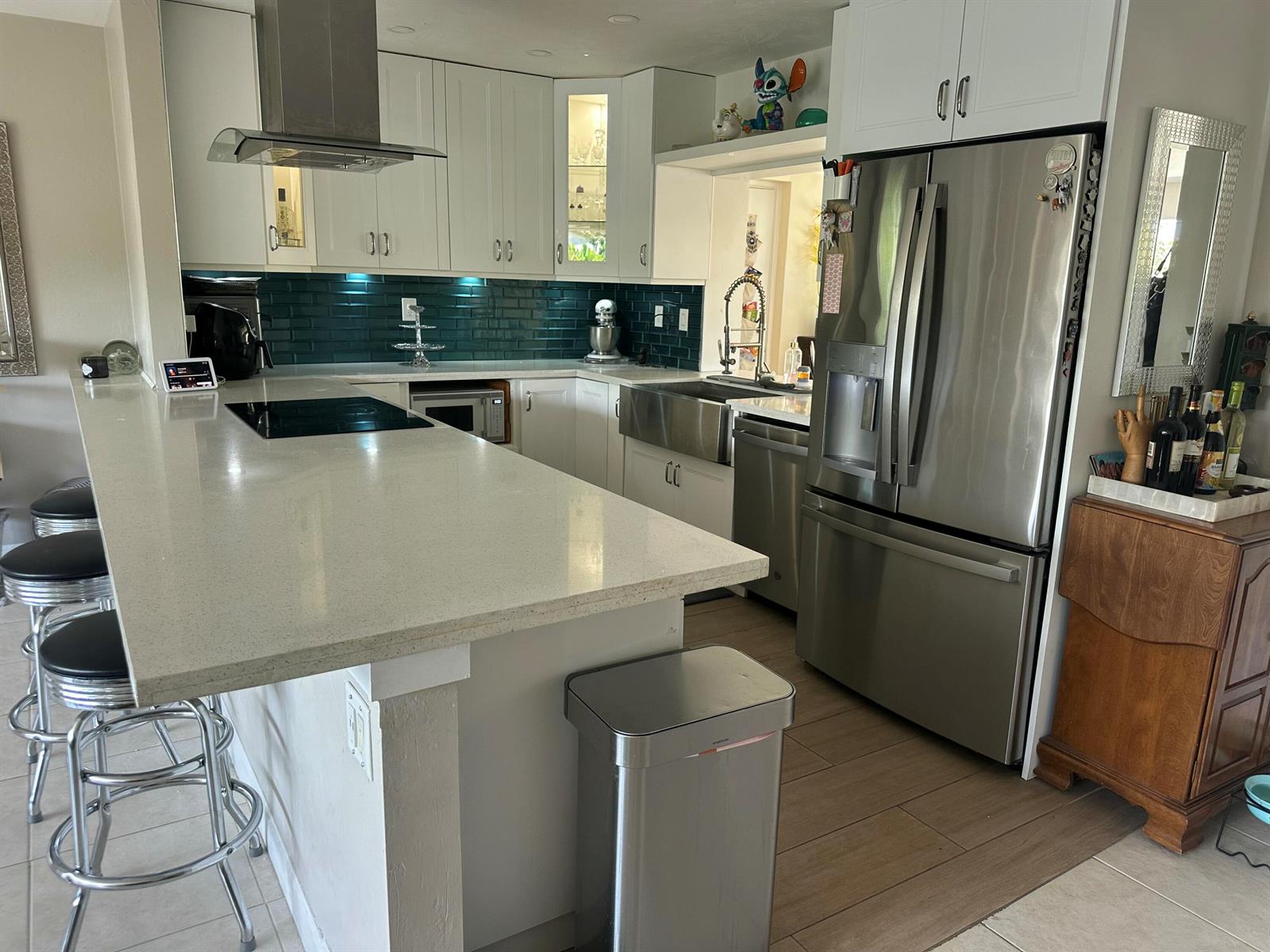 A kitchen features white cabinets, a teal subway tile backsplash, stainless steel appliances, and island seating — 2099 S Conference Drive, Boca Raton FL 33486, BOCA RATON, FL