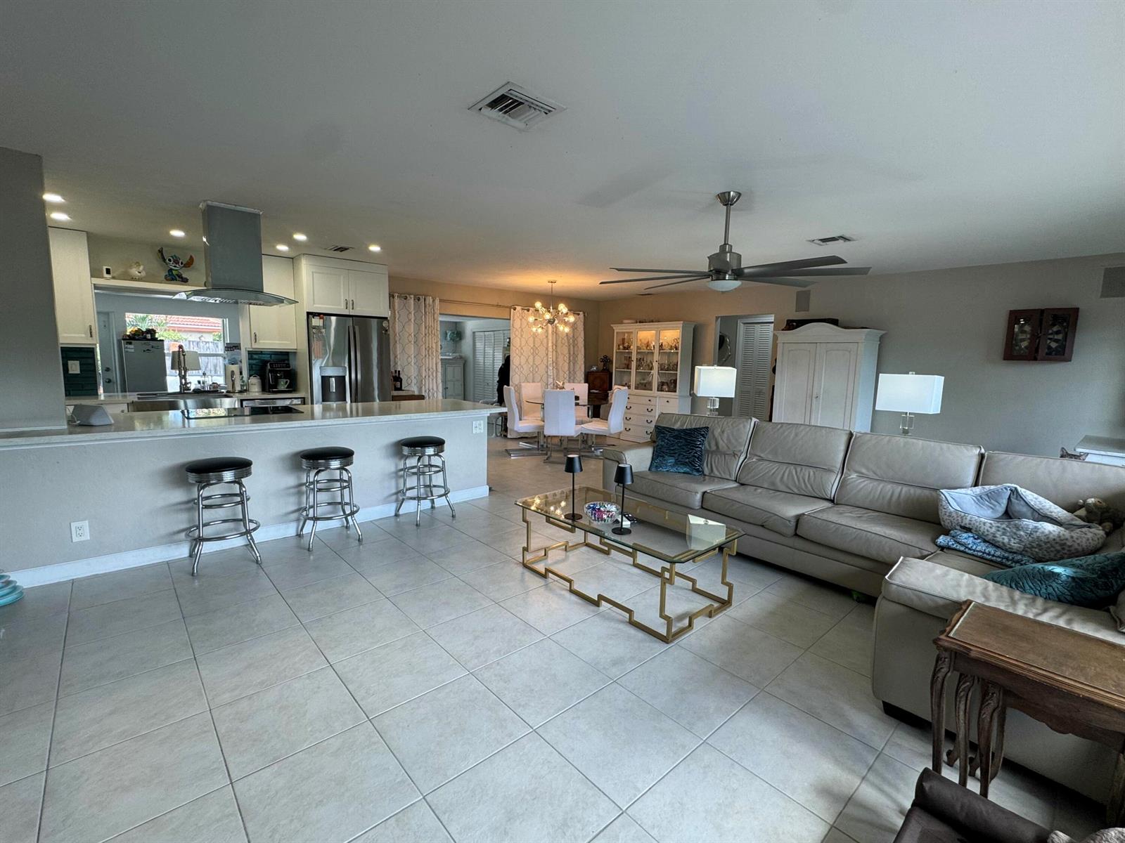 An open-concept living room and kitchen featuring tile floors, a sectional sofa, and bar seating — 2099 S Conference Drive, Boca Raton FL 33486, BOCA RATON, FL