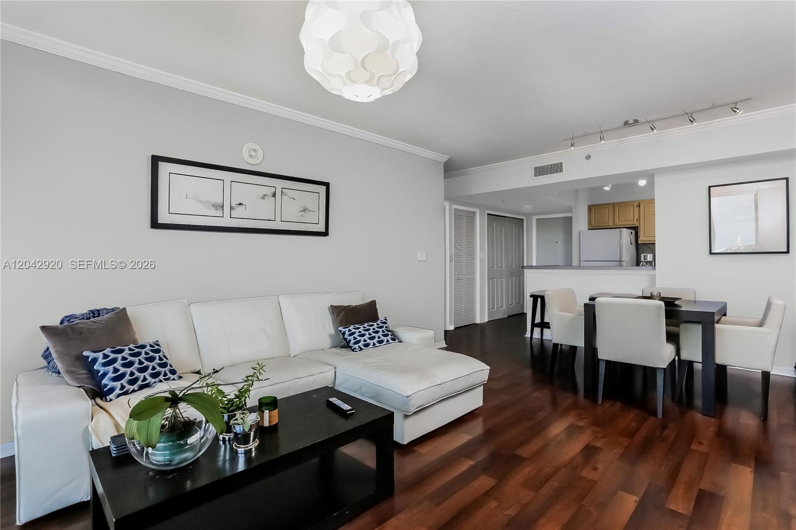 A living room and dining area feature white furniture, dark wood floors, and a pendant light — 2665 SW 37th Ave # 1404, Miami FL 33133, MIAMI, FL