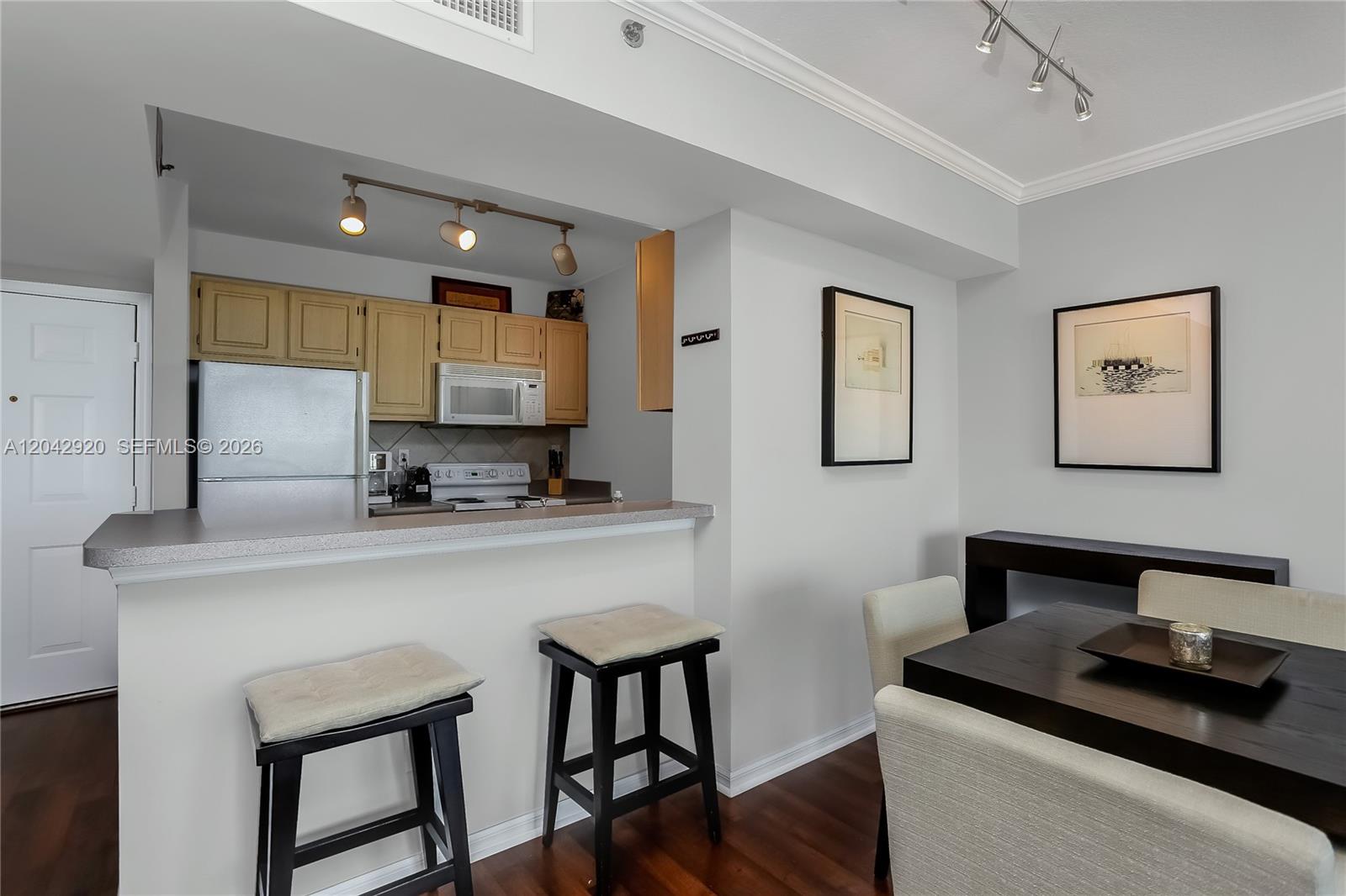 A kitchen with light wood cabinets and a breakfast bar overlooks a dining area — 2665 SW 37th Ave # 1404, Miami FL 33133, MIAMI, FL