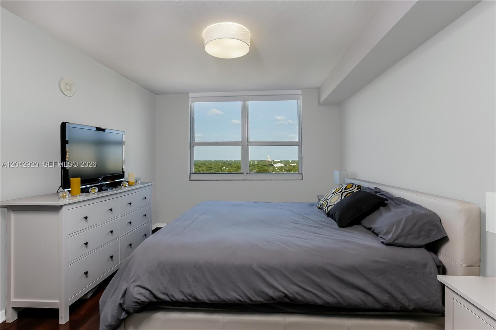 A bedroom features a bed with grey bedding, a white dresser, and a large window — 2665 SW 37th Ave # 1404, Miami FL 33133, MIAMI, FL