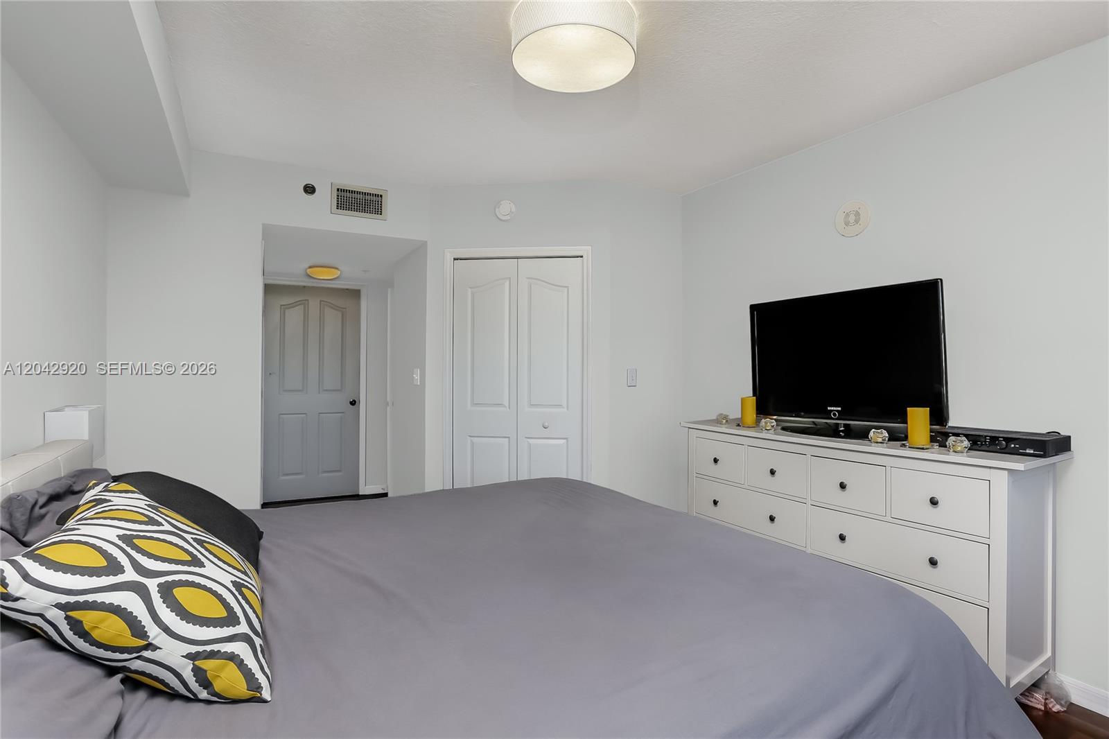 A bedroom features a bed with gray bedding, a white dresser, and a television — 2665 SW 37th Ave # 1404, Miami FL 33133, MIAMI, FL