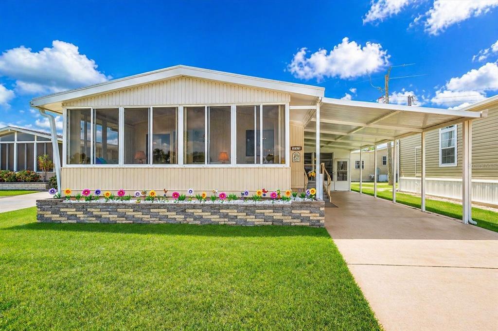 A manufactured home with a screened-in porch, stone-veneer planter, and a covered carport — 132 LAKEVIEW DRIVE UNIT 132, PALMETTO, FL