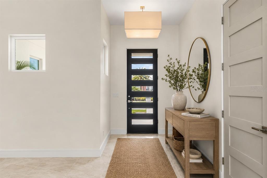 A bright entryway features a black front door, a wooden console table, and a jute rug — 9352 BORDET COURT, ORLANDO, FL