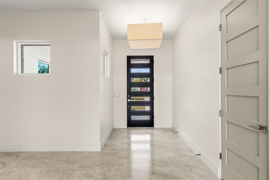 A bright entryway features light tile flooring, a modern black front door, and a pendant light — 9352 BORDET COURT, ORLANDO, FL