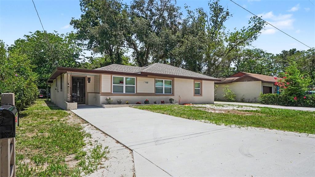A single-story house with a beige exterior, a brown roof, and a concrete driveway — 1109 NW 14TH AVENUE, OCALA, FL