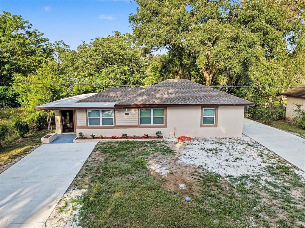 A single-story house with a beige exterior, a brown shingled roof, and a concrete driveway — 1109 NW 14TH AVENUE, OCALA, FL