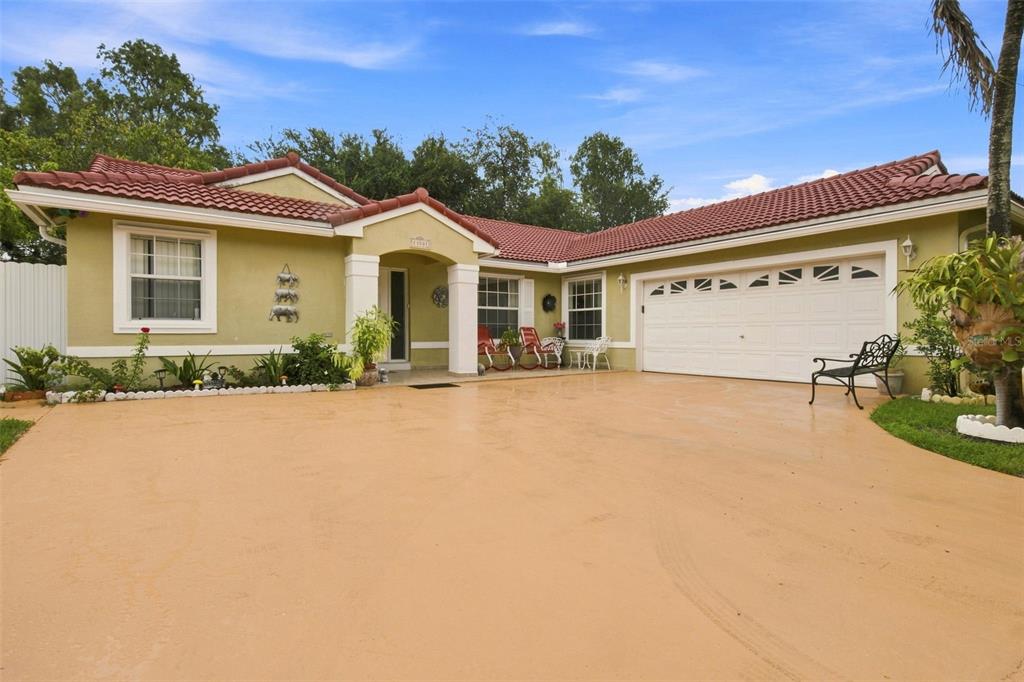 A single-story house with a red tile roof, beige stucco walls, and a large driveway — 13501 SW 17TH COURT, MIRAMAR, FL