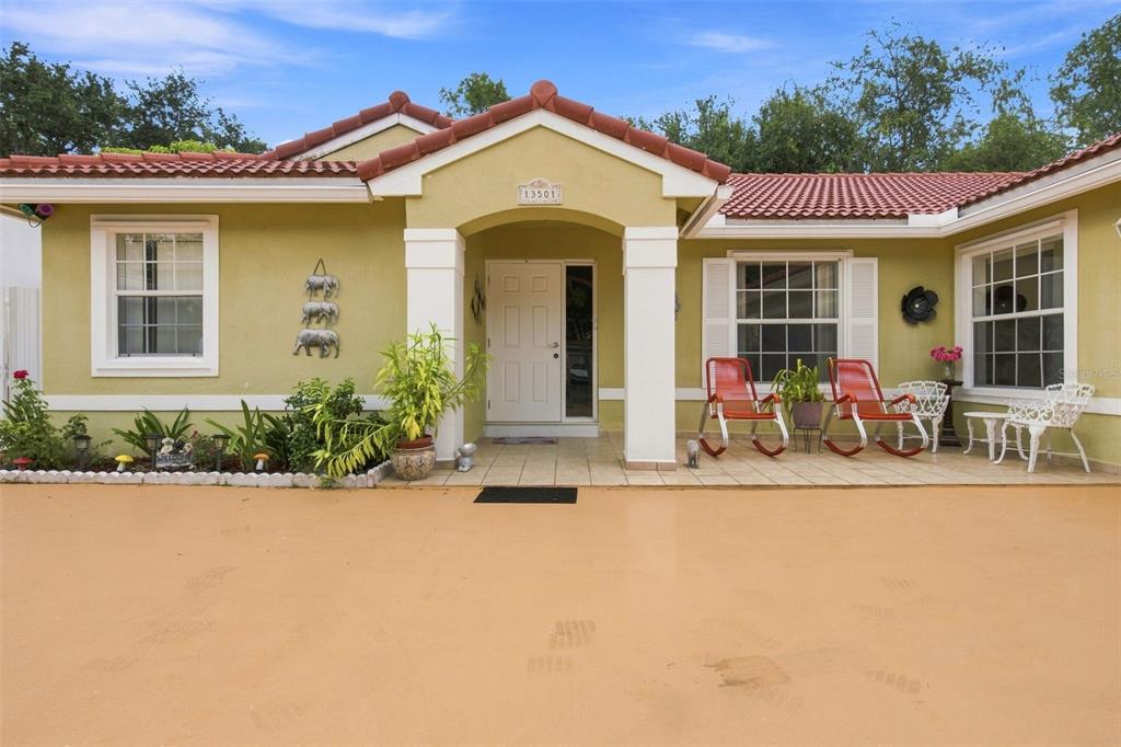 The exterior of a single-story house features a tiled roof, light green siding, and a porch — 13501 SW 17TH COURT, MIRAMAR, FL