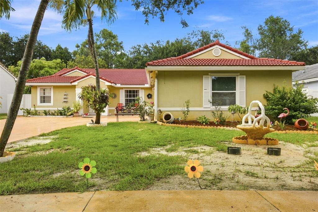A single-story house with a red tile roof and yellow stucco exterior sits behind a lawn — 13501 SW 17TH COURT, MIRAMAR, FL