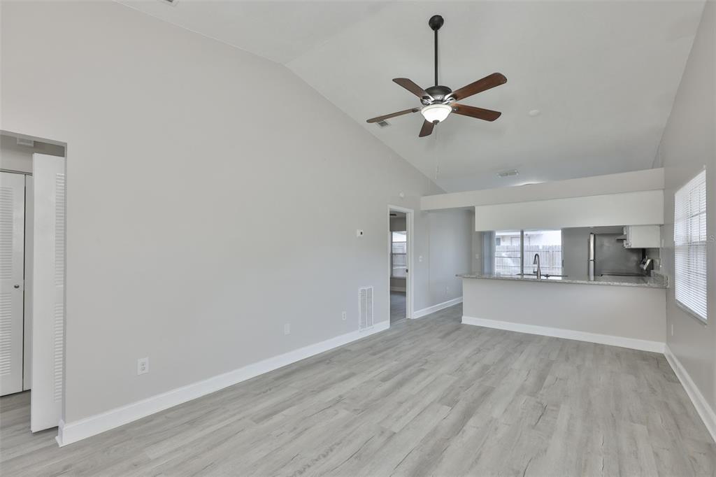 A living room with light gray walls, wood-look flooring, a ceiling fan, and an open kitchen — 1720 OAK BRANCH COURT, BRANDON, FL