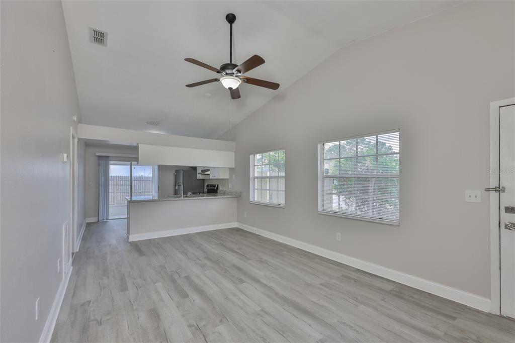A living room with light gray walls, wood-look flooring, a ceiling fan, and an open kitchen — 1720 OAK BRANCH COURT, BRANDON, FL