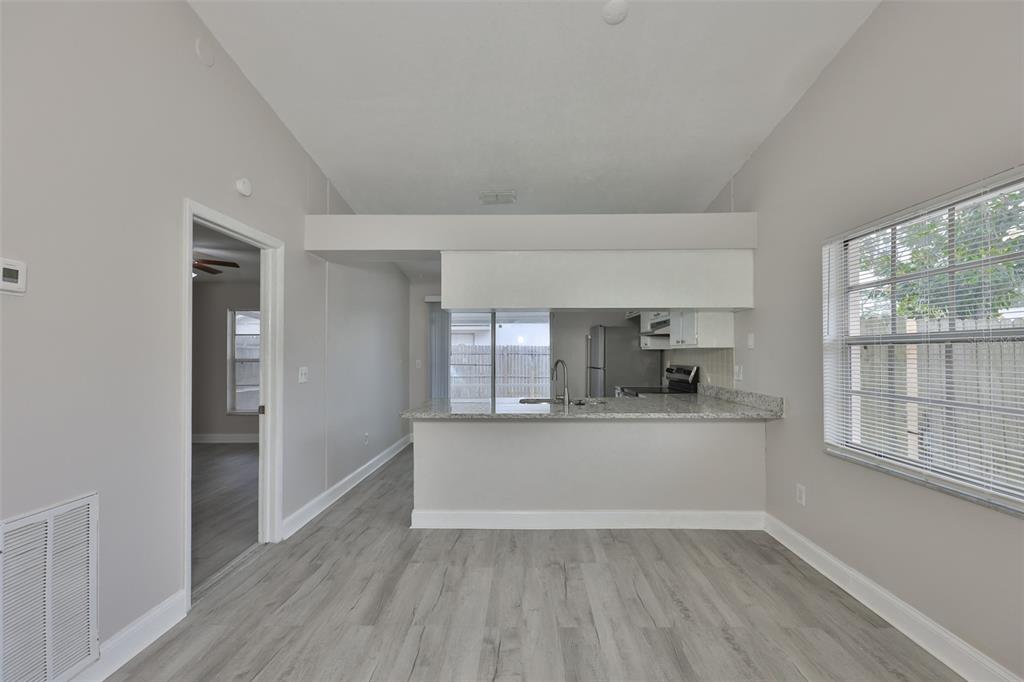A living room with light gray flooring leads to a kitchen with a granite breakfast bar — 1720 OAK BRANCH COURT, BRANDON, FL