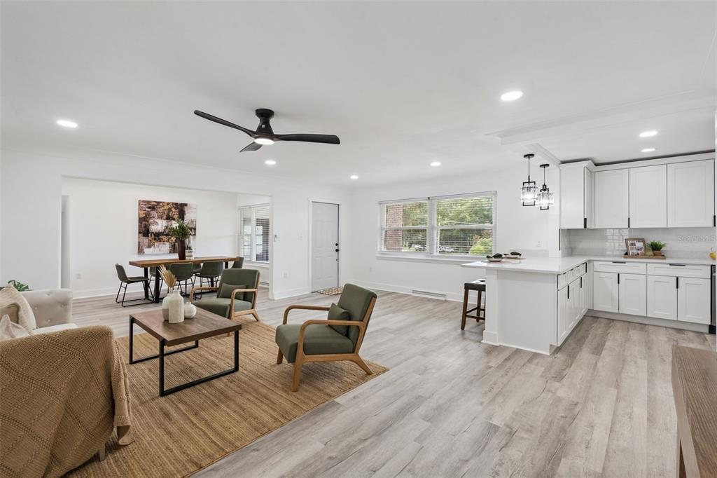 An open-concept living room and kitchen feature white cabinets, light wood flooring, and modern furniture — 1510 OVERLOOK DRIVE, MOUNT DORA, FL