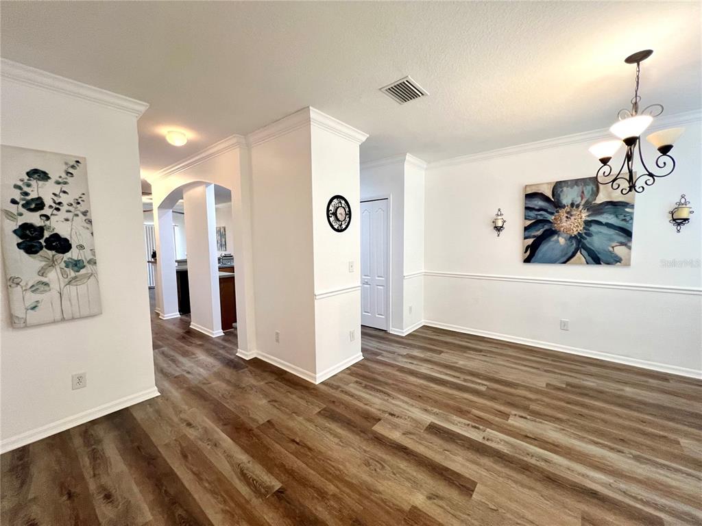 A dining room with wood-look flooring, white walls, a chandelier, and two floral wall paintings — 12425 FOXMOOR PEAK DRIVE, RIVERVIEW, FL
