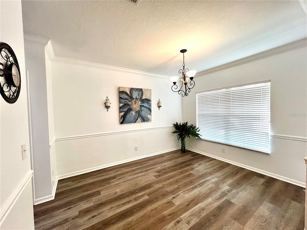 A dining room features wood-look flooring, a chandelier, a floral wall art piece, and blinds — 12425 FOXMOOR PEAK DRIVE, RIVERVIEW, FL